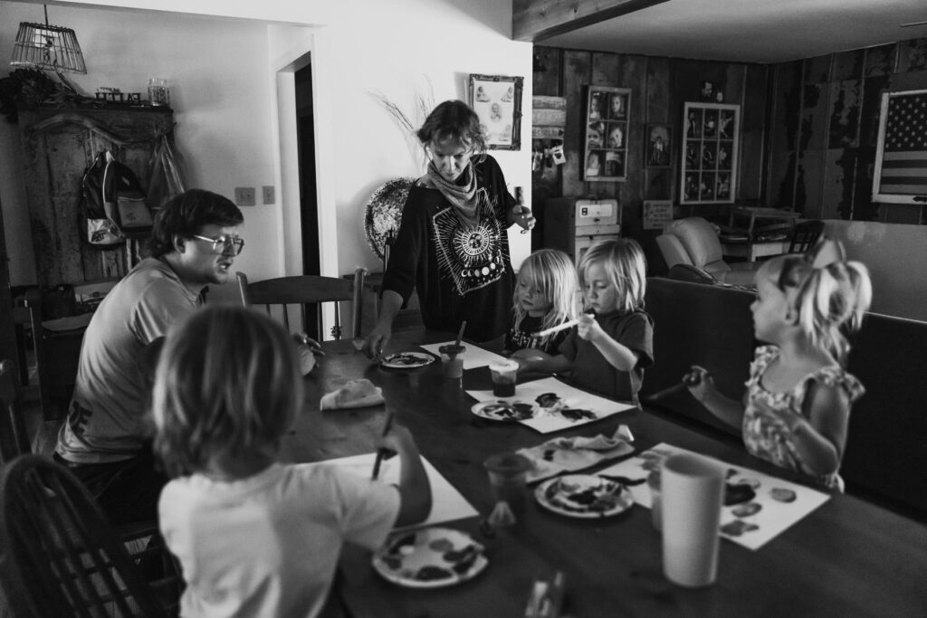 A family with 4 young children gathered for an art project, candid