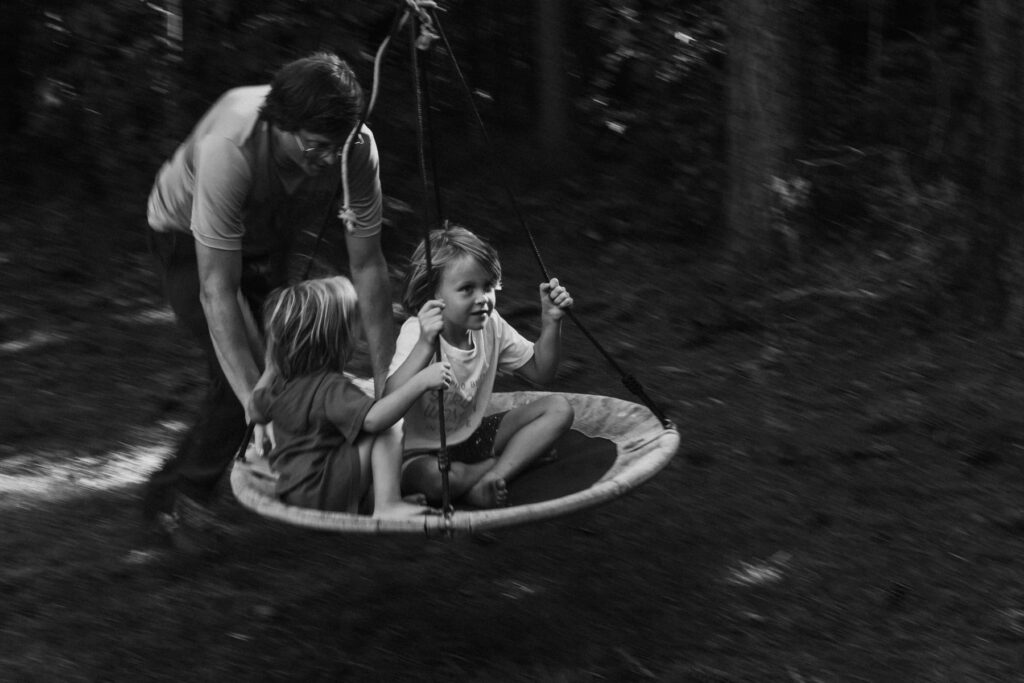 a father pushing his kids on a disc swing