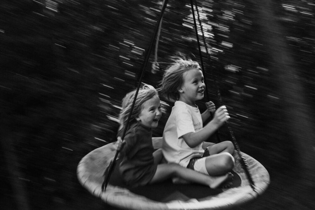 2 young children smiling on a disc swing