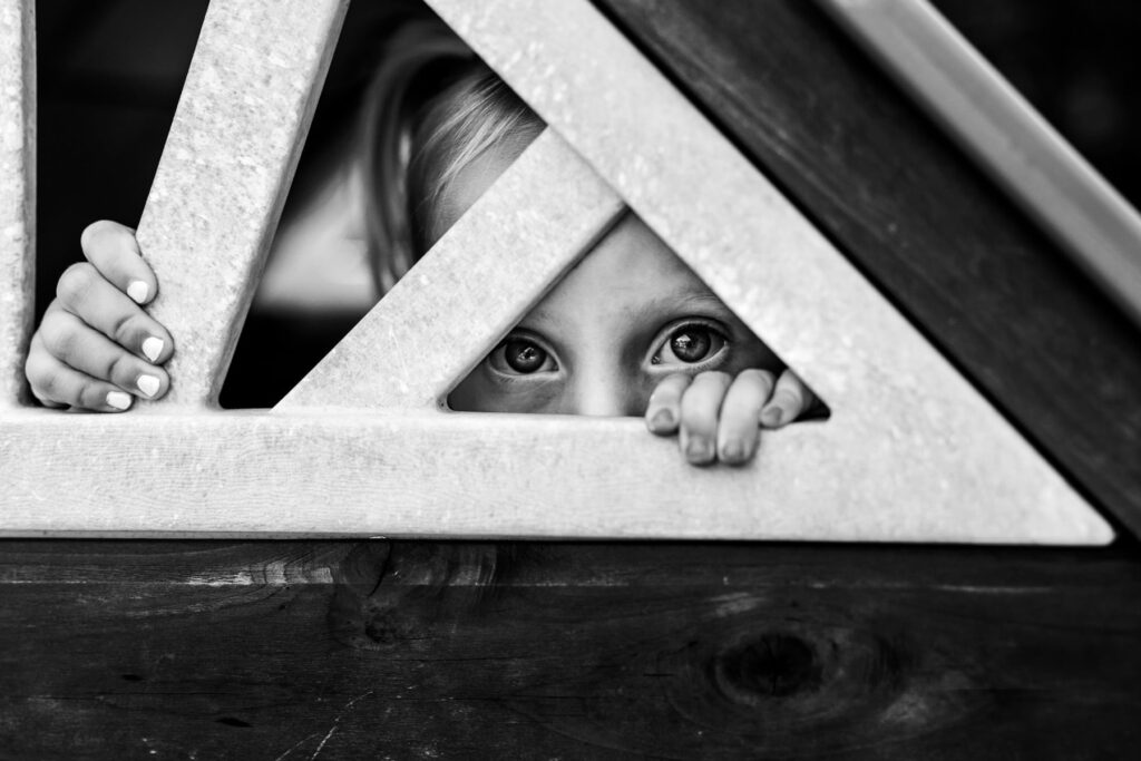 a young girl peeking from inside a playhouse