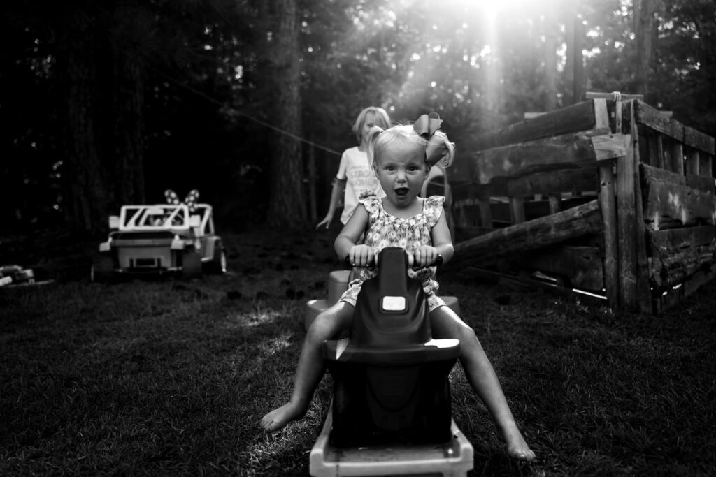 young girl on a backyard toy excited, candid
