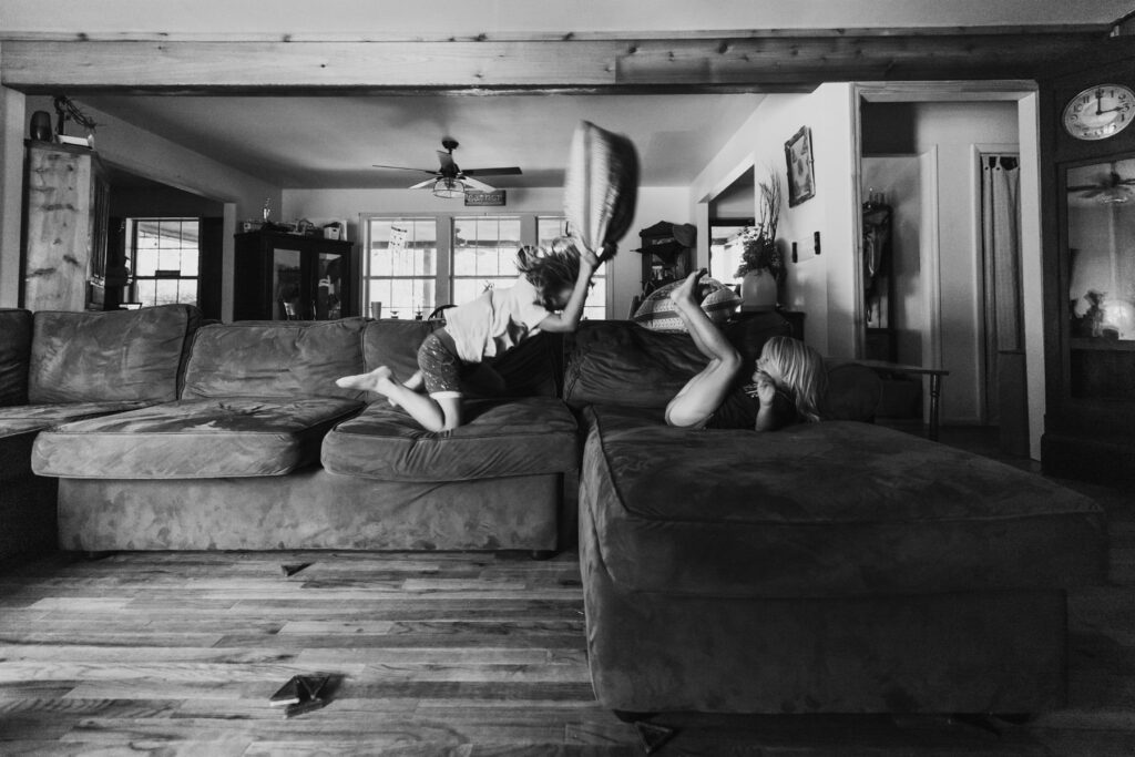 2 kids having a couch pillow fight from a documentary family session