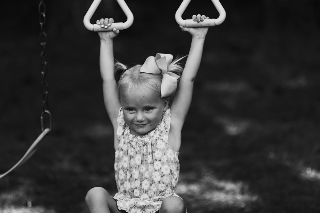Young girl hanging on a playset, smiling