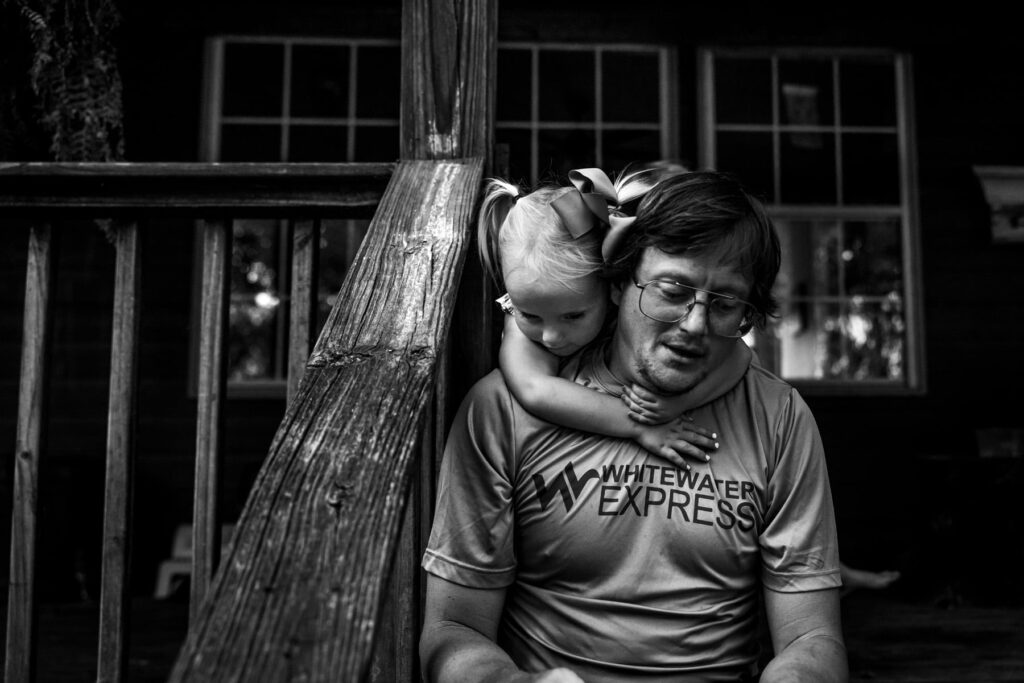 a young girl hugging on her father over his shoulders